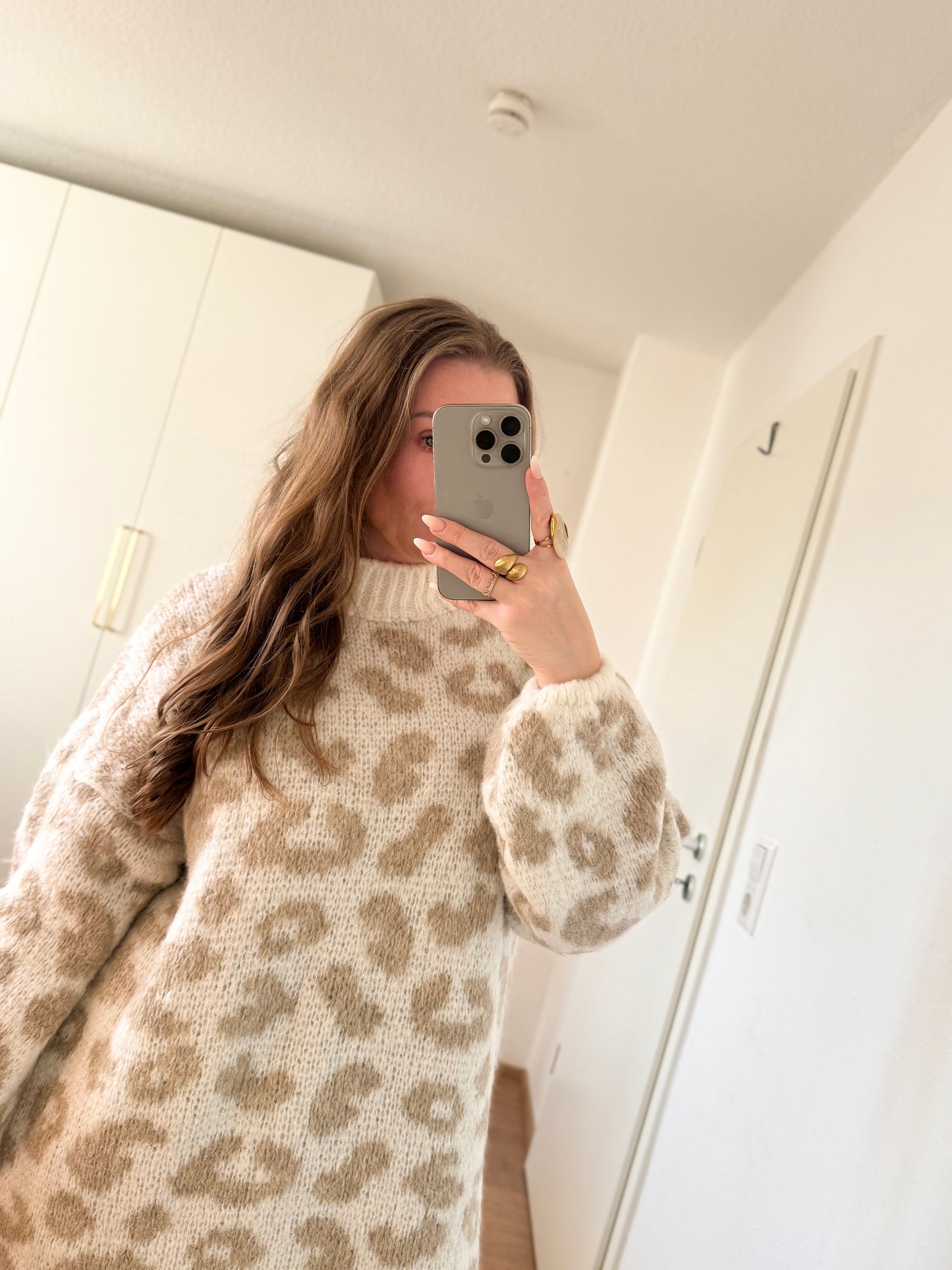 Model trägt ein beigefarbenes Leo-Strickkleid mit kuscheliger Struktur, geeignet für Größen 36 bis 42.